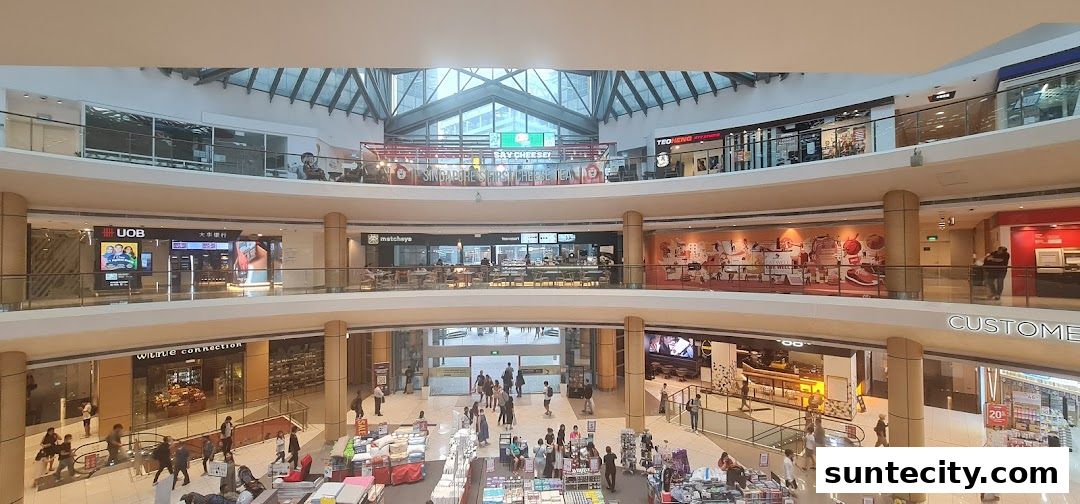 A wide shot of the interior of a multi-level shopping mall with various shops and shoppers.
