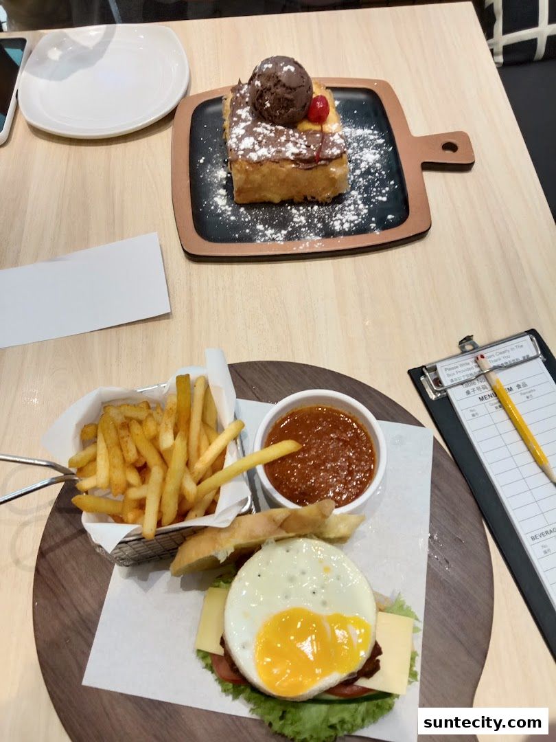 A delicious meal featuring a burger with a fried egg, fries, and a sweet dessert with ice cream.