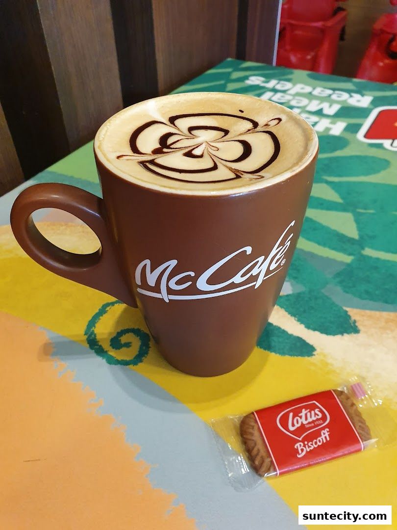 A McCafe coffee with latte art and a Lotus Biscoff cookie.