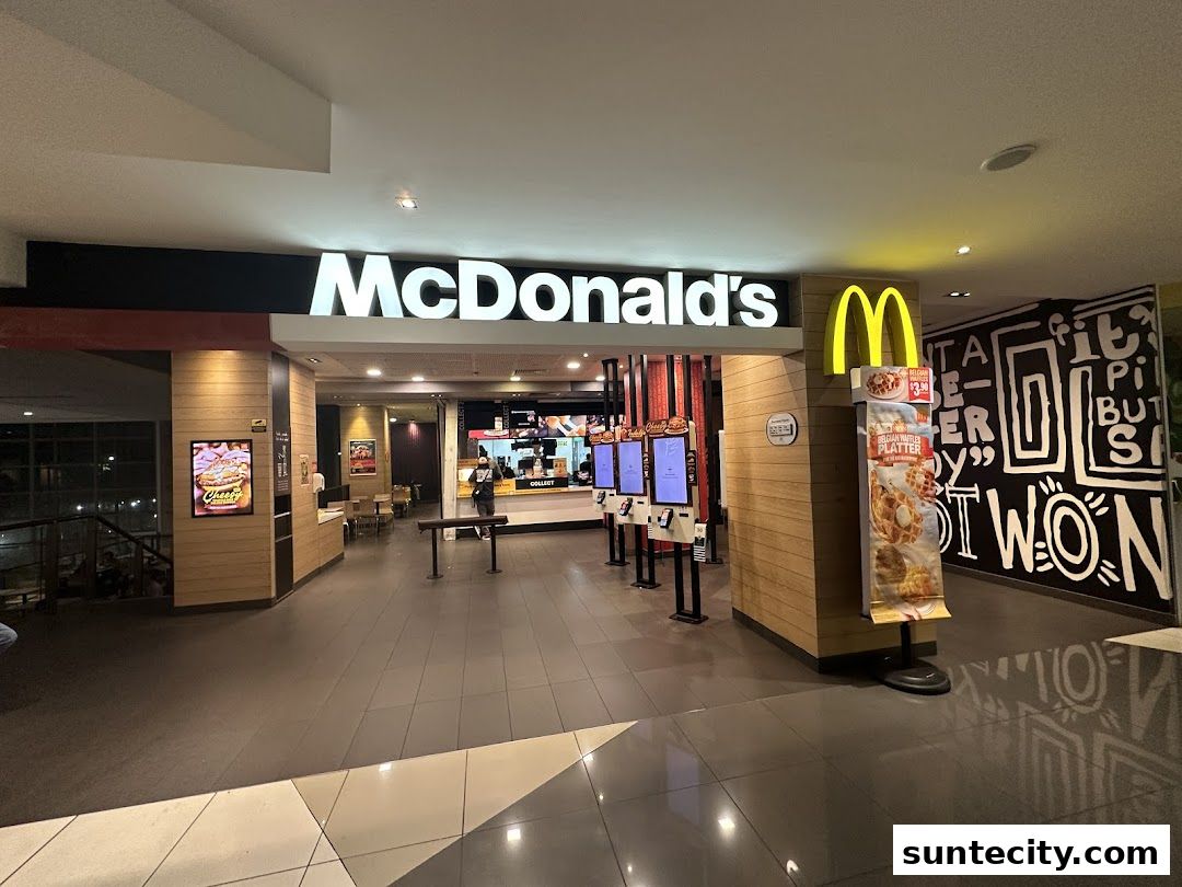 The entrance to a McDonald's restaurant with digital ordering kiosks and promotional displays.