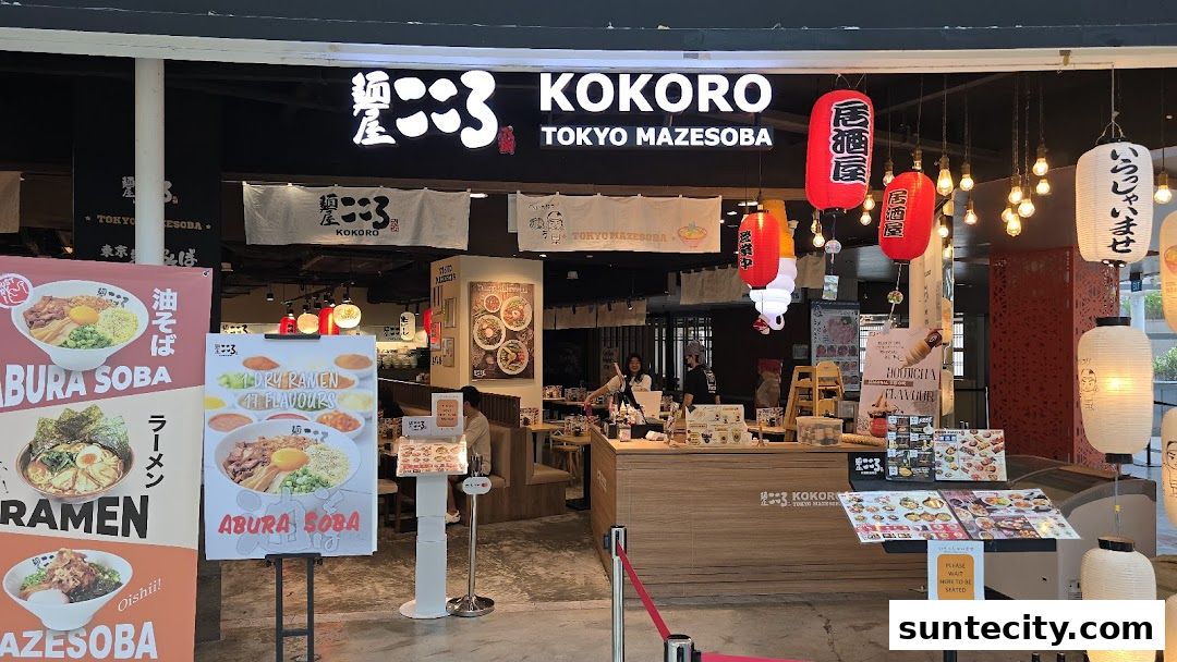 The exterior of Menya Kokoro, a Tokyo Mazesoba restaurant, with vibrant banners and lanterns.