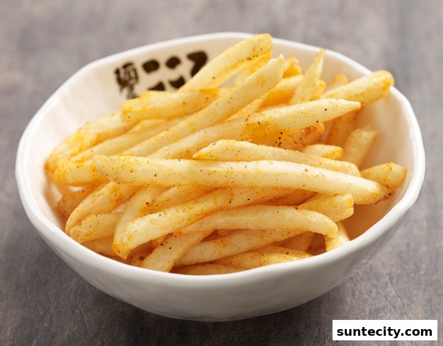 A bowl of seasoned french fries with a textured grey background.