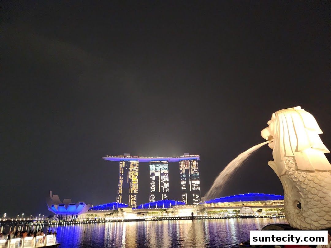 Night view of the Merlion statue spouting water with Marina Bay Sands in the background.