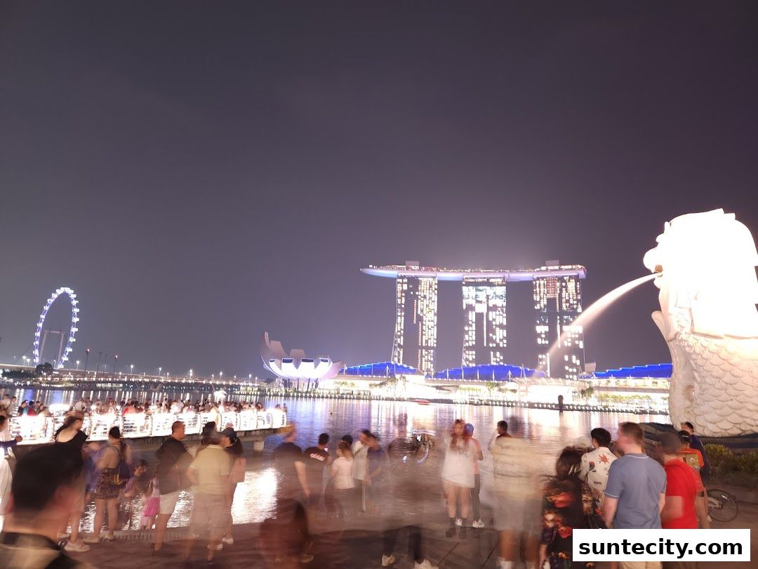 Night view of Singapore's iconic Merlion statue with Marina Bay Sands and Singapore Flyer in the background.