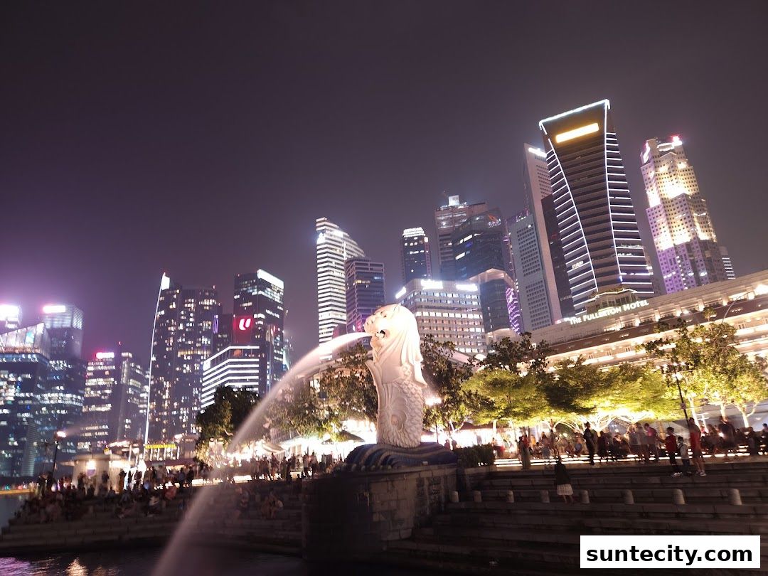 Night view of the Singapore skyline featuring the Merlion statue and illuminated skyscrapers.