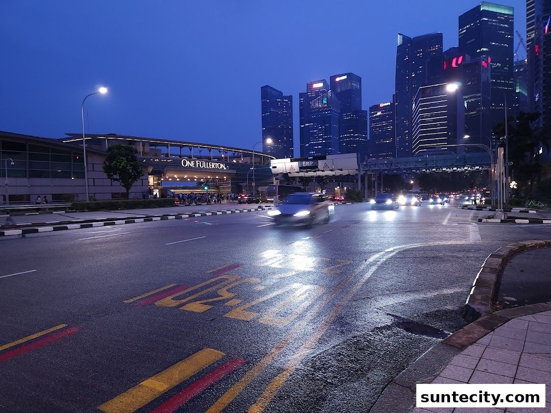 A street view at dusk with the "One Fullerton" building and city skyline in the background.