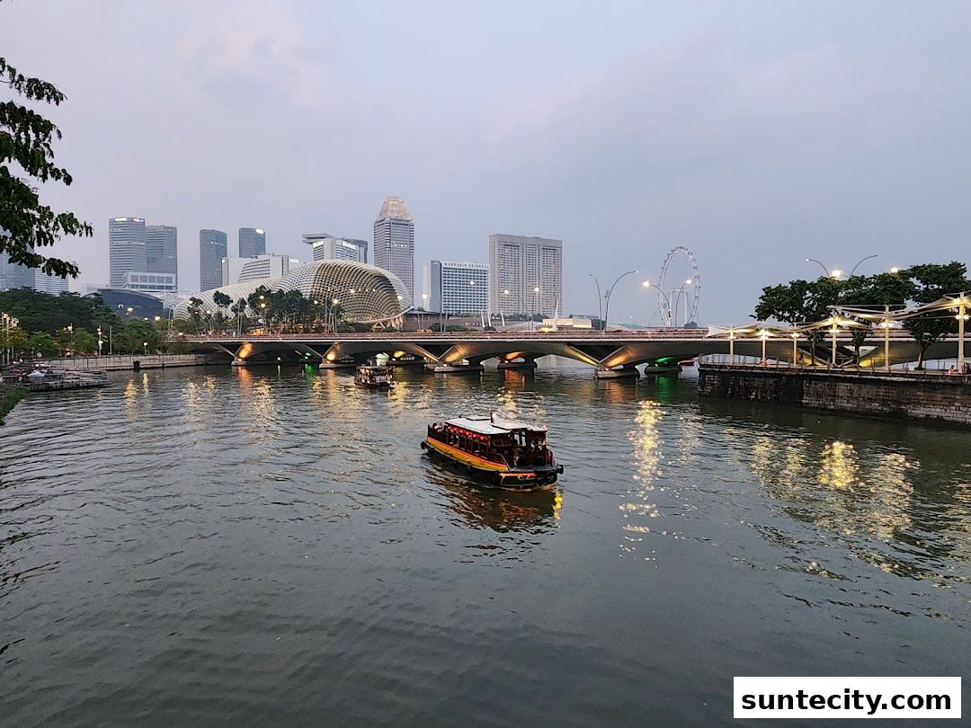 A scenic view of a river with boats, a bridge, and city skyline at dusk.
