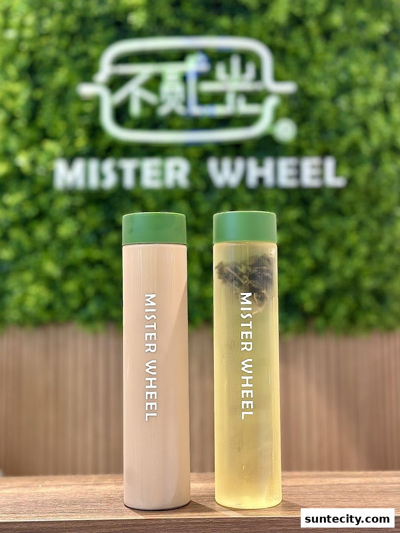 Two tall bottles, one with a creamy beverage and one with green tea, stand on a wooden surface.