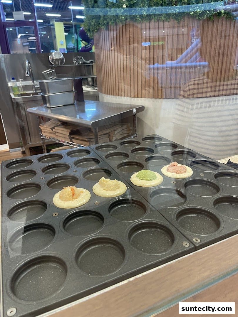 A close-up of a waffle maker with batter and fillings for wheel cakes.