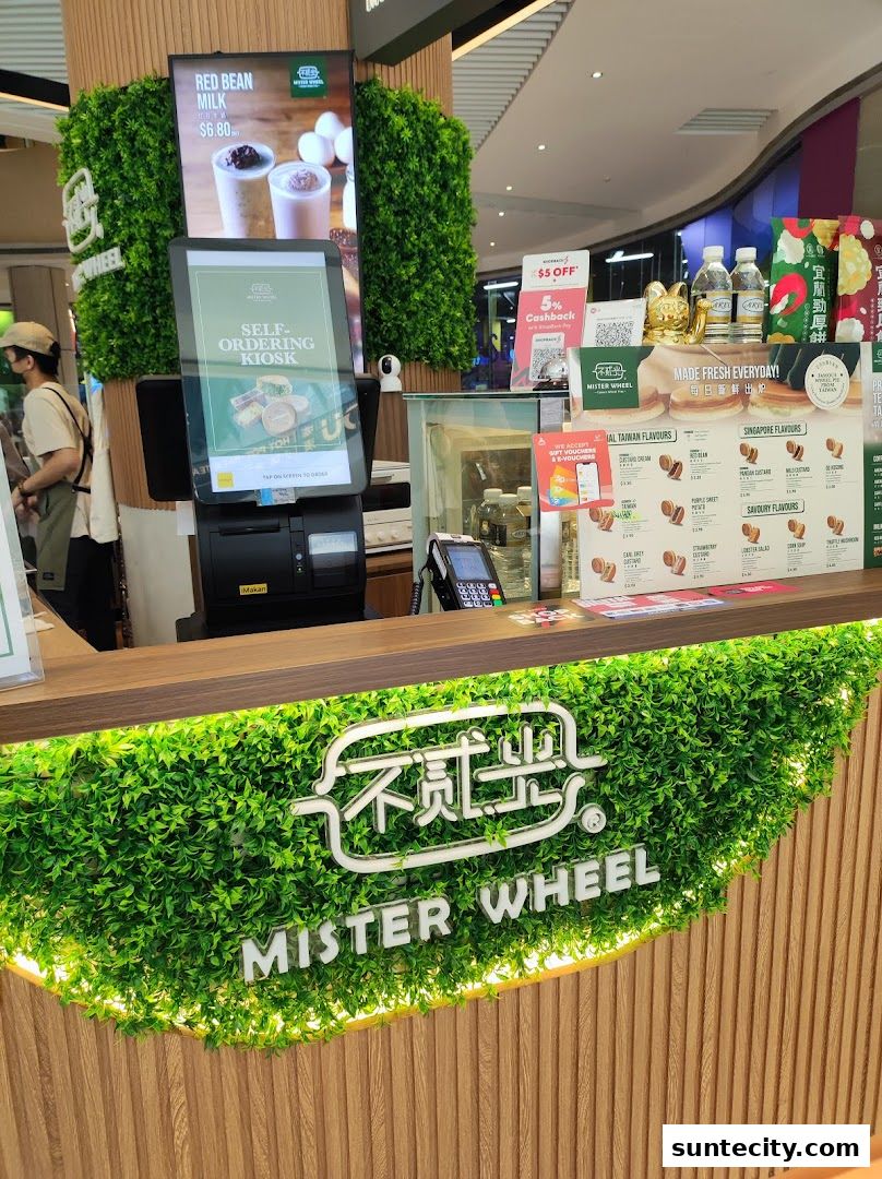 A counter at Mister Wheel Singapore with a self-ordering kiosk and menu displays.