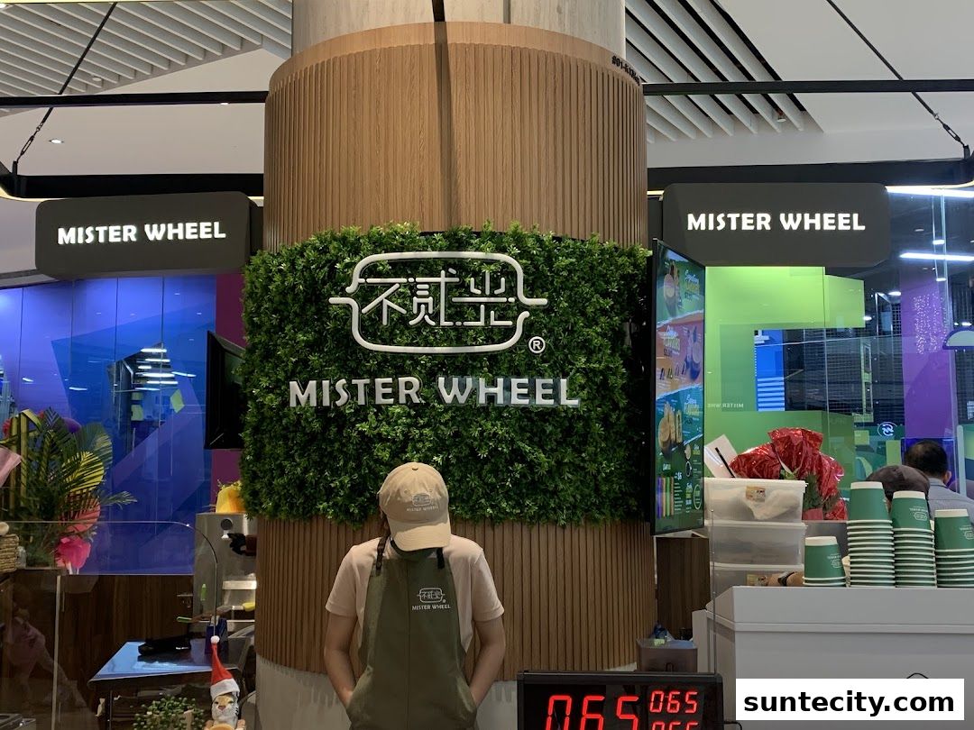 A Mister Wheel shop with a green wall, signage, and a staff member behind the counter.
