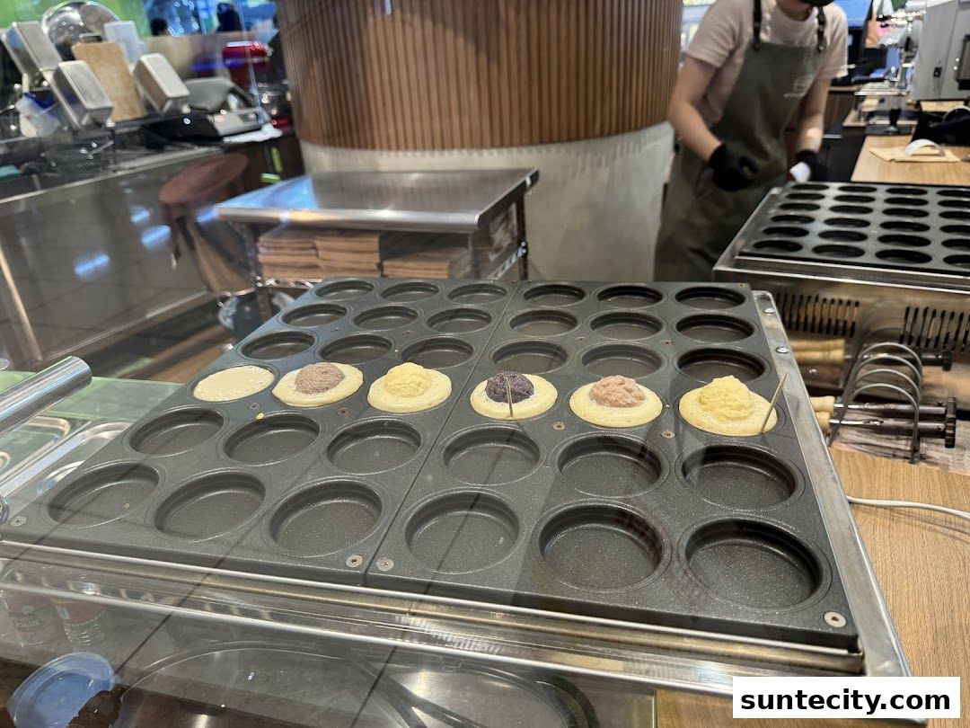 A close-up of a waffle maker with batter and fillings for wheel cakes.