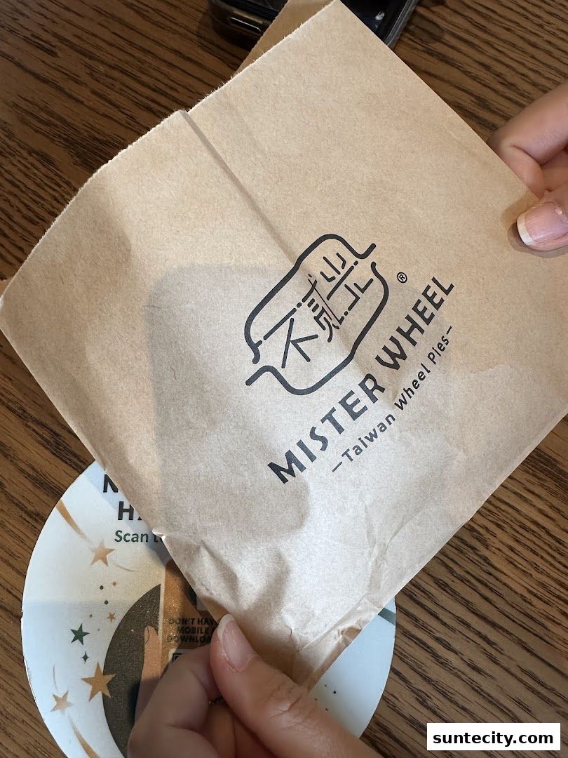 A person holding a brown paper bag with the Mister Wheel logo and text.