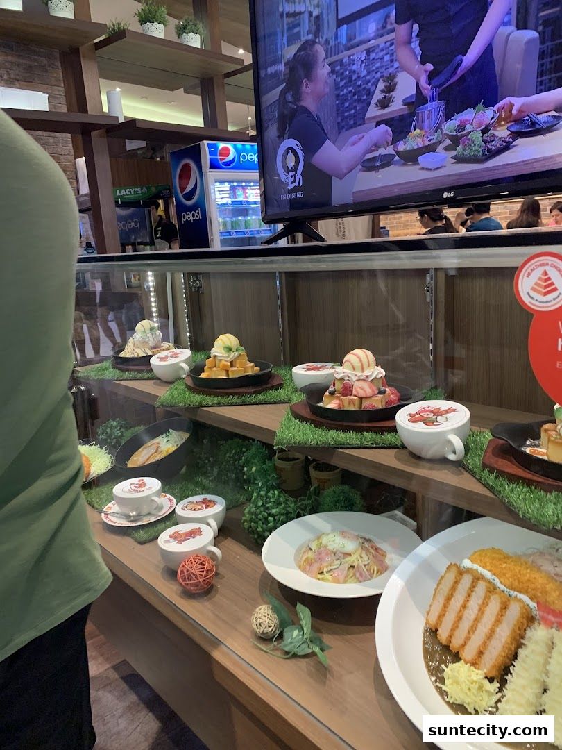 A display case showcasing various food items and a television screen showing a dining scene.