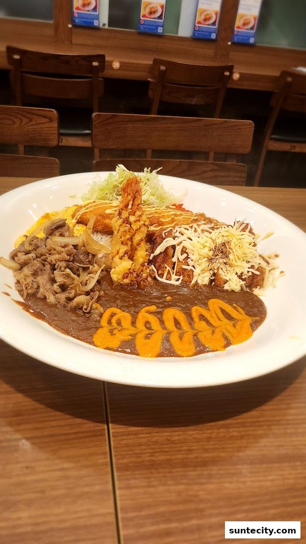 A large plate of Japanese curry with rice, beef, fried shrimp, and cheese.