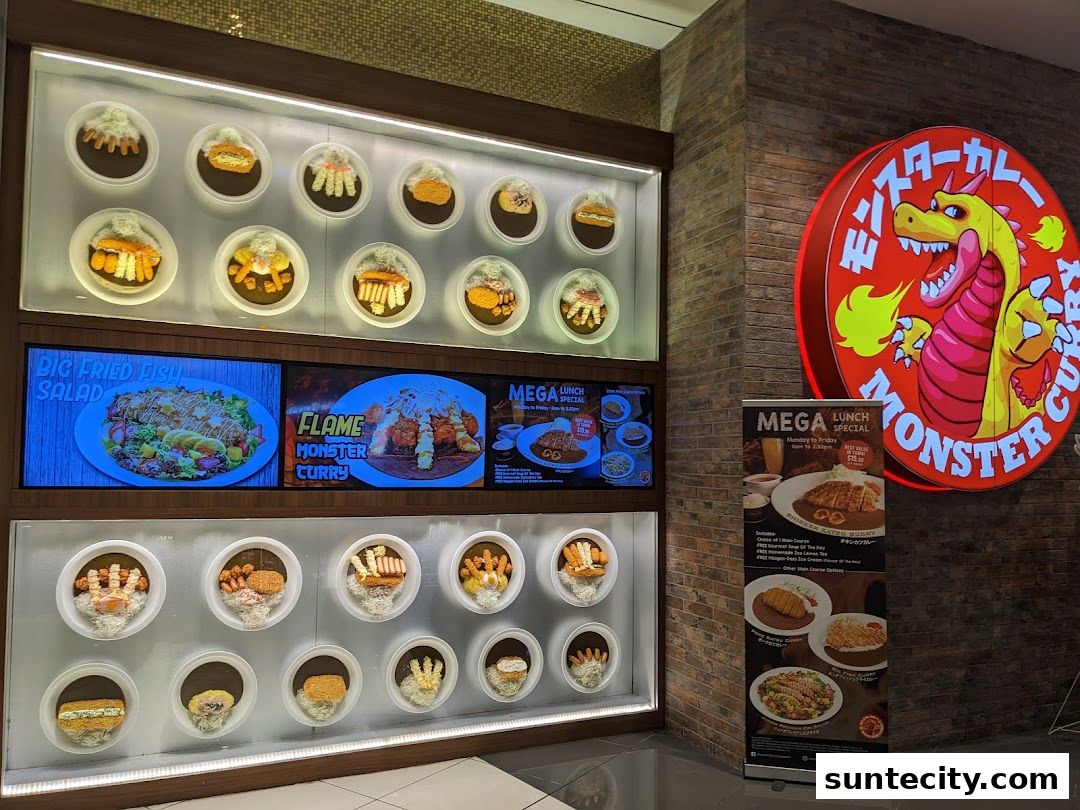 Monster Curry shop front with a large illuminated sign and a display of curry dishes.