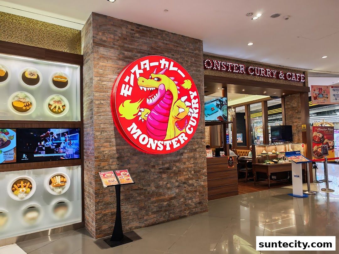 The exterior of Monster Curry & Cafe, featuring a large circular logo and displays of curry dishes.