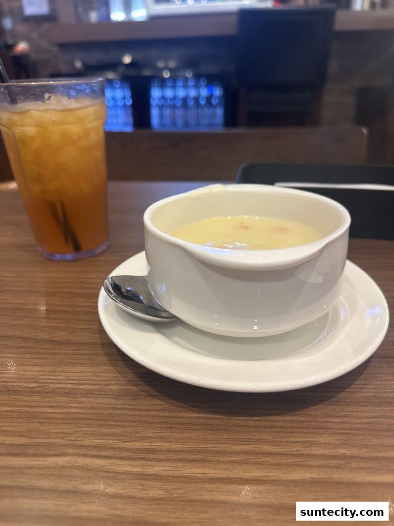 A bowl of soup and a glass of iced tea on a wooden table.