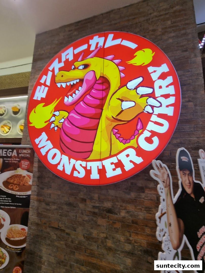 A vibrant sign for Monster Curry featuring a cartoon dragon and a promotional poster.