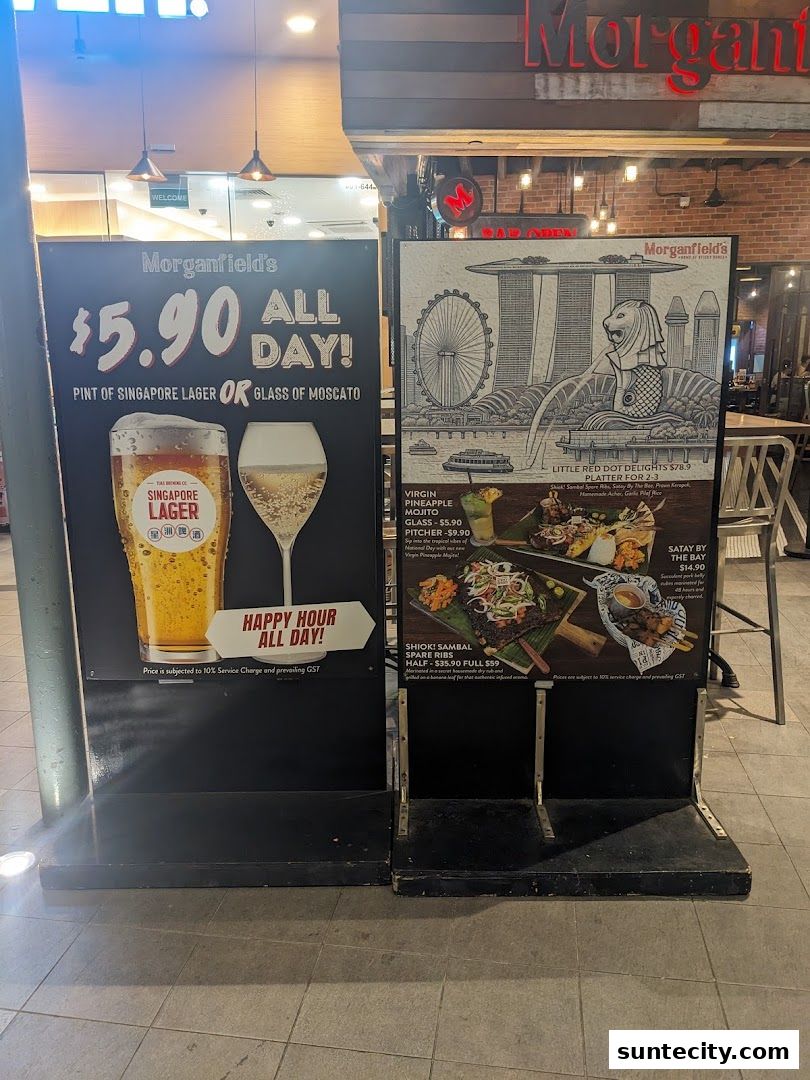 Promotional boards outside Morganfield's restaurant showcasing happy hour deals and food platters.