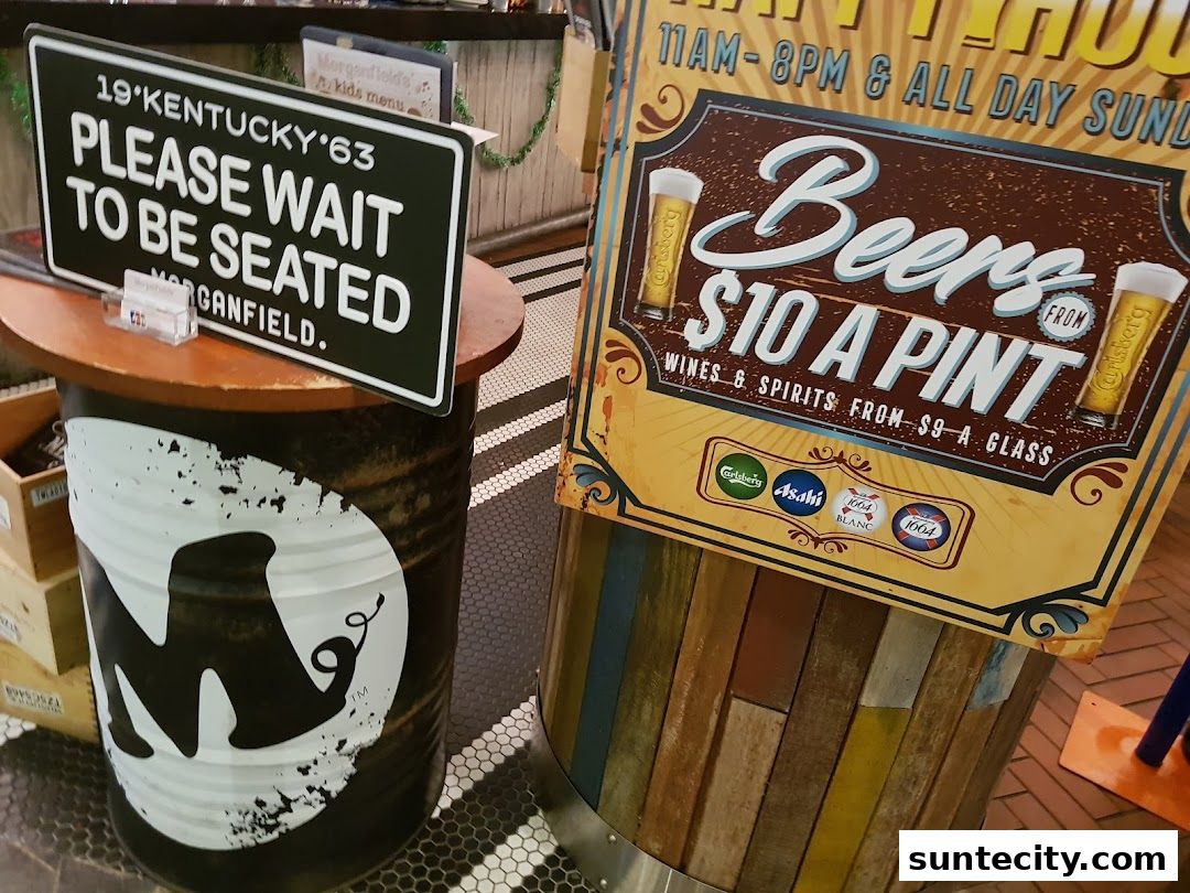 A sign indicating to wait to be seated at Morganfield's, next to a beer promotion.