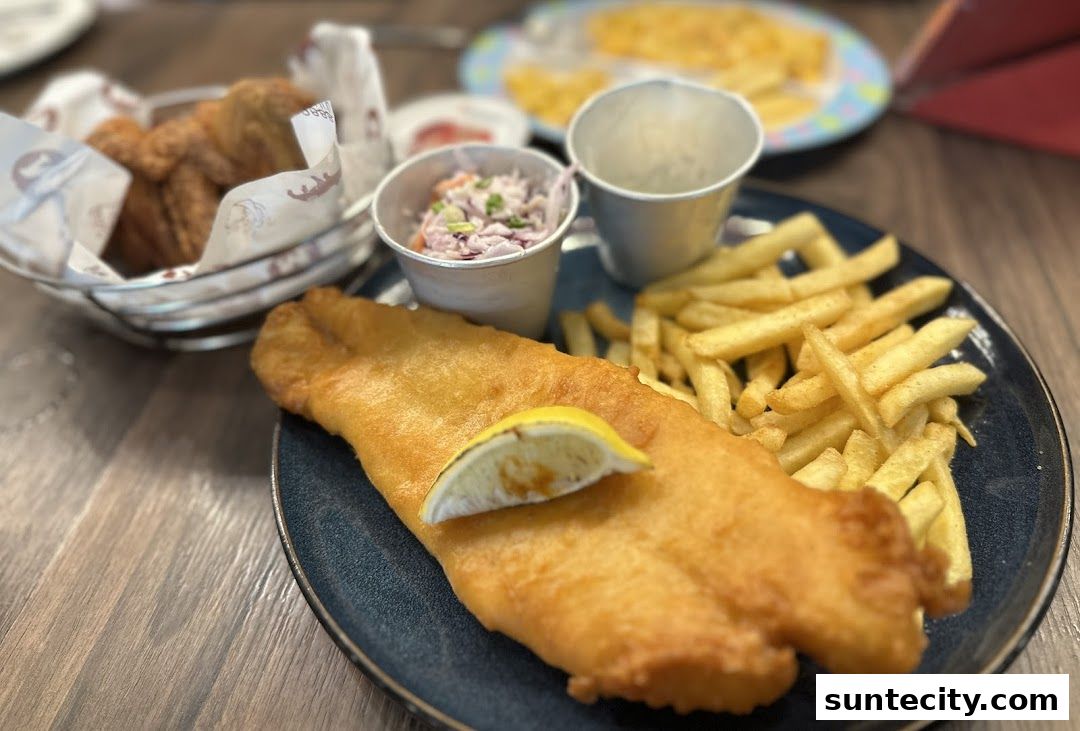 A plate of fish and chips with coleslaw and a lemon wedge.
