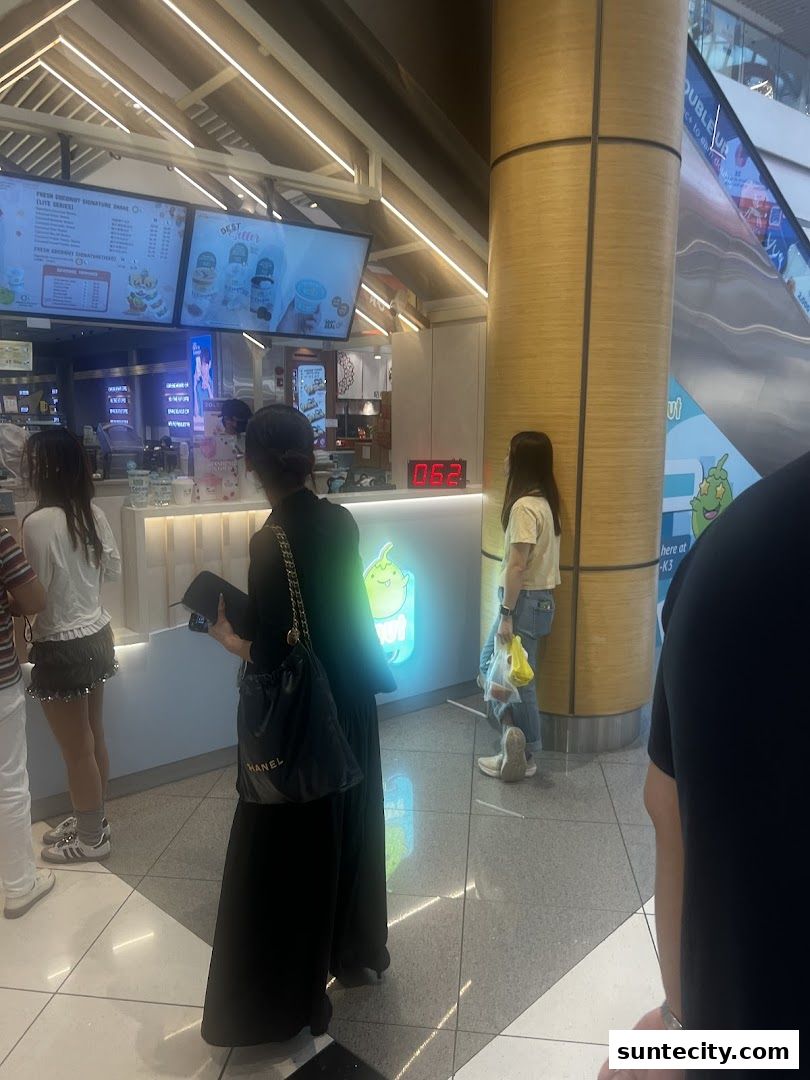 People queuing at a Mr. Coconut outlet with a menu board and illuminated signage.