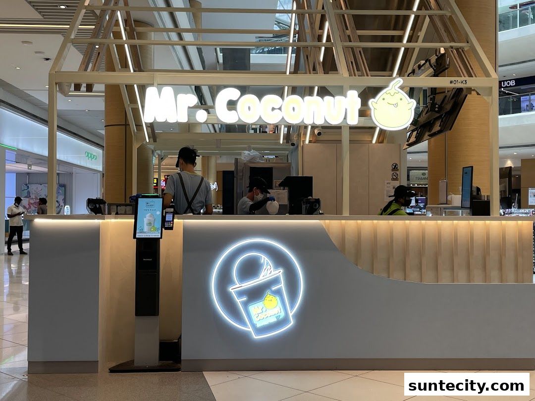 The Mr. Coconut shop front with staff serving customers and a digital menu display.