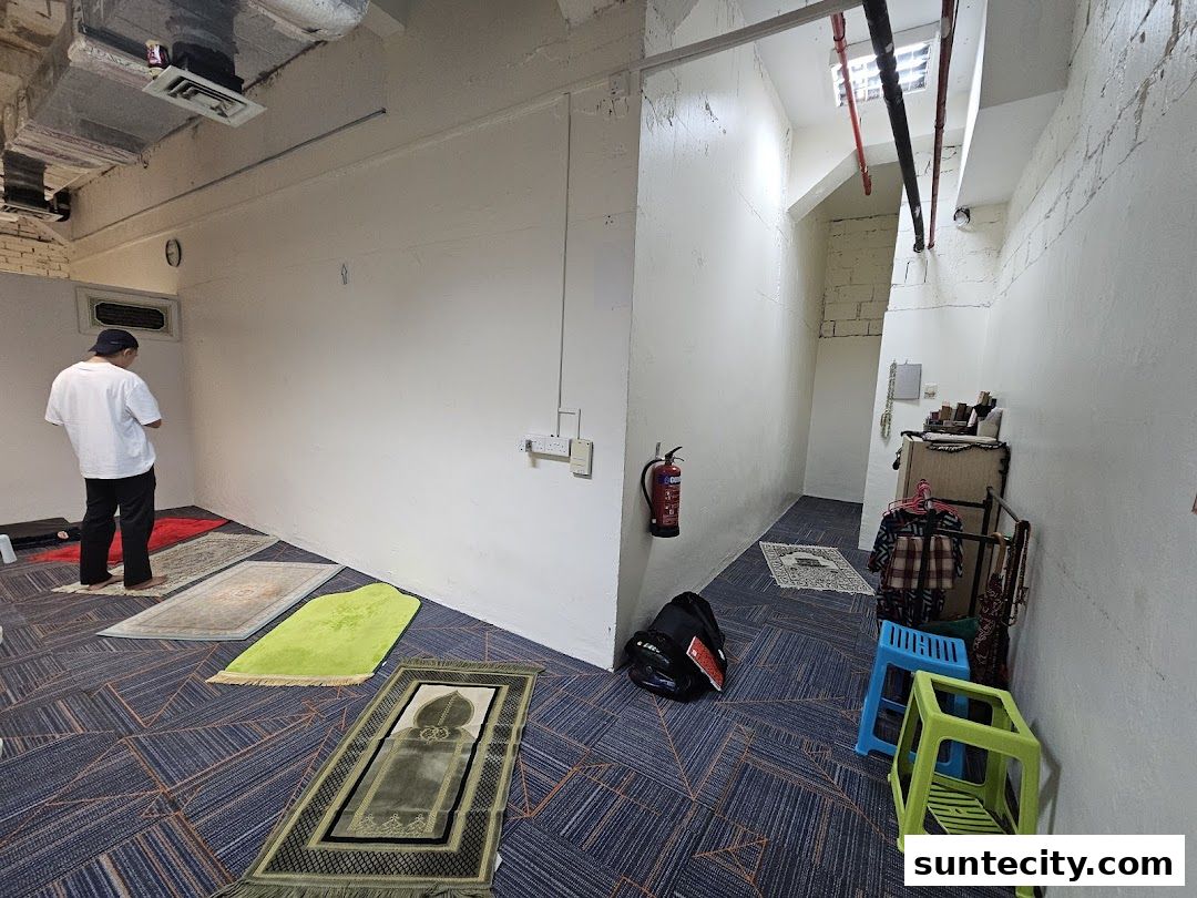 A person praying on prayer mats in a clean, well-lit room with a fire extinguisher.