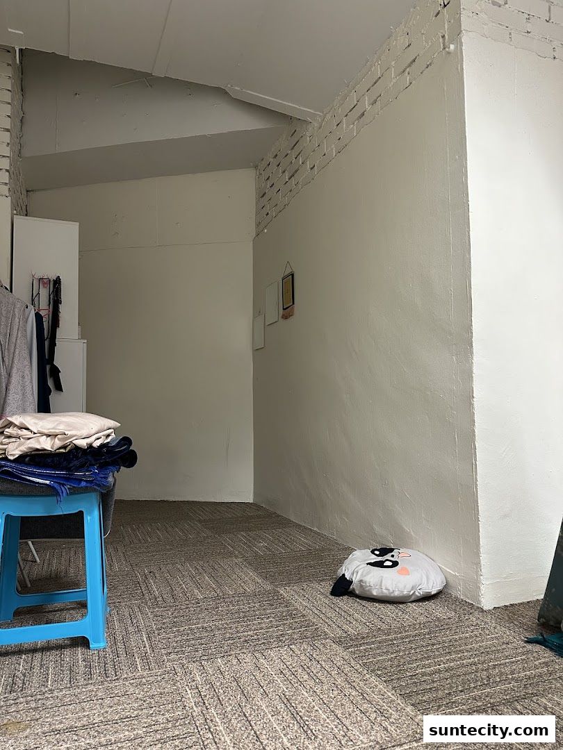 Interior shot of a room with a blue stool, folded clothes, and a decorative pillow.