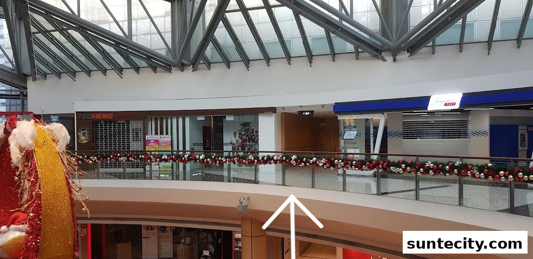 A view of shops on an upper level of a mall, decorated with festive garlands.