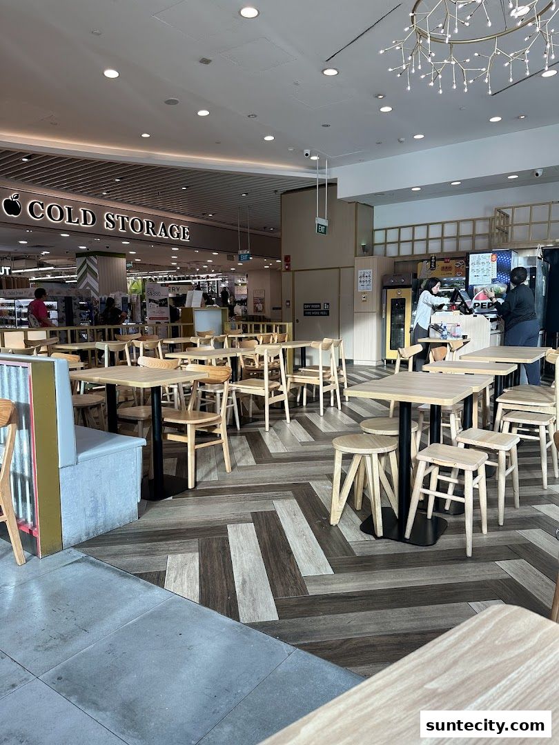 Interior view of a dining area with wooden tables and chairs, adjacent to a Cold Storage supermarket.