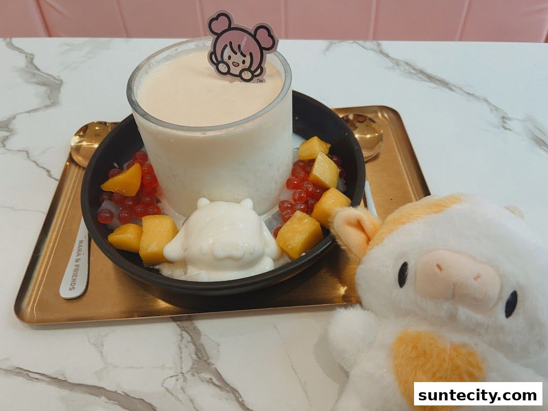 A cute dessert with mango, boba, and a character topping, next to a plush toy.