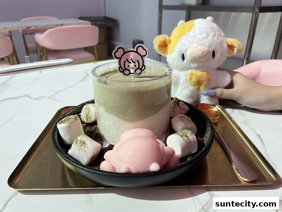 A delicious dessert with matcha, marshmallows, and red bean paste, served with a cute cow plushie.