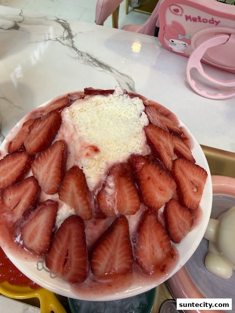 A refreshing strawberry shaved ice dessert topped with fresh strawberries and condensed milk.