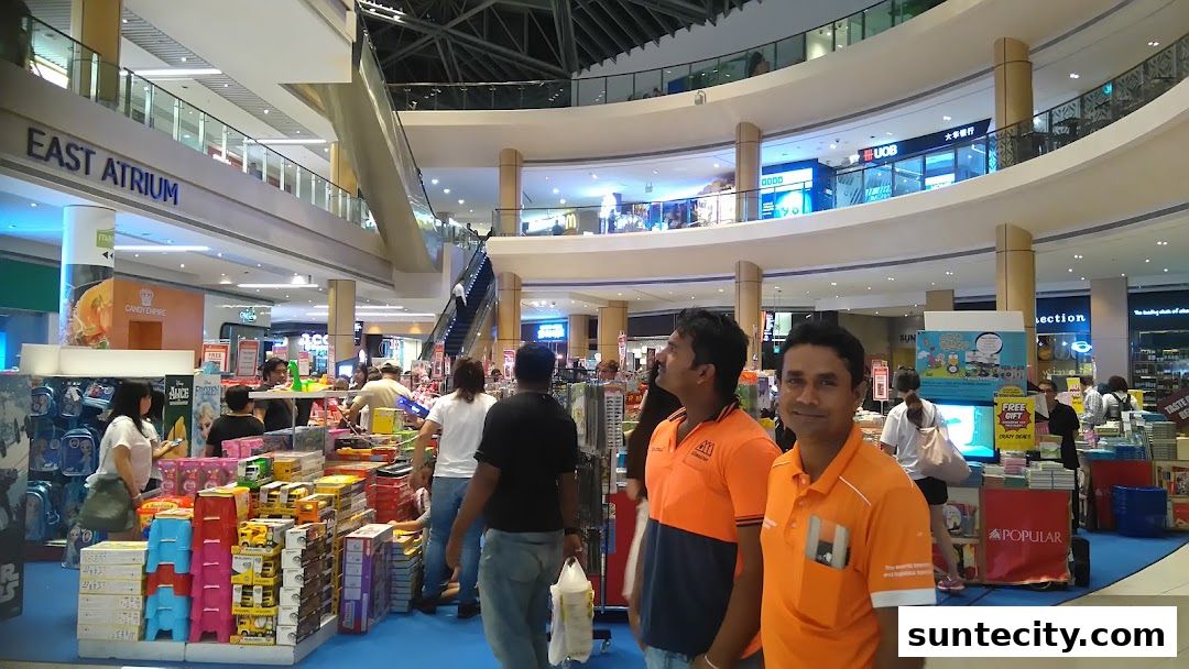 People browsing merchandise in a busy shopping mall atrium with multiple levels.