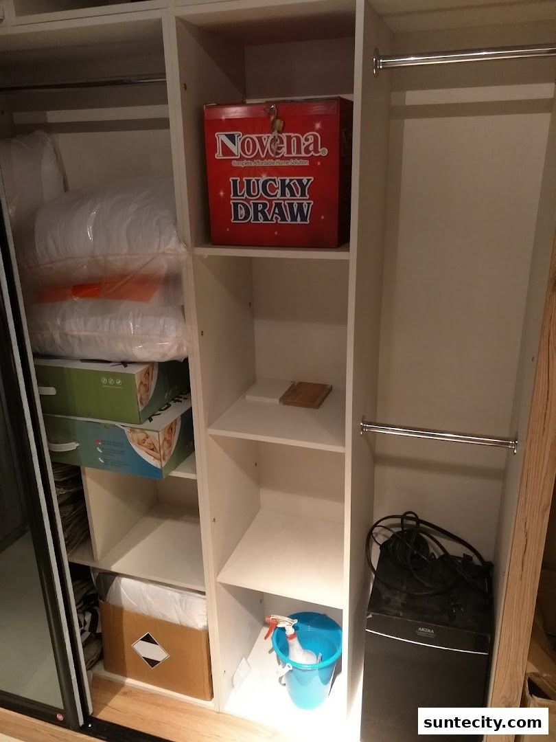 Interior view of a white closet with shelves containing various items, including bedding and a lucky draw box.