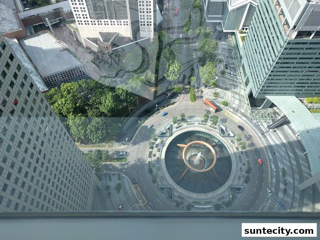 Aerial view of a city street with a fountain and surrounding buildings.