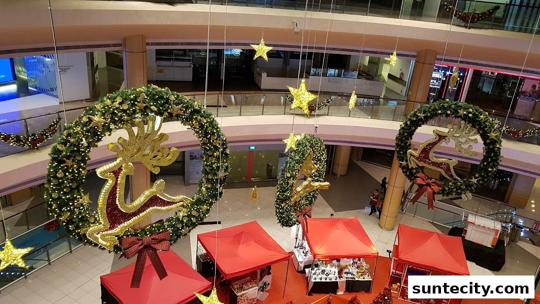 A festive Christmas display with large wreaths, reindeer, stars, and market stalls in a shopping mall.