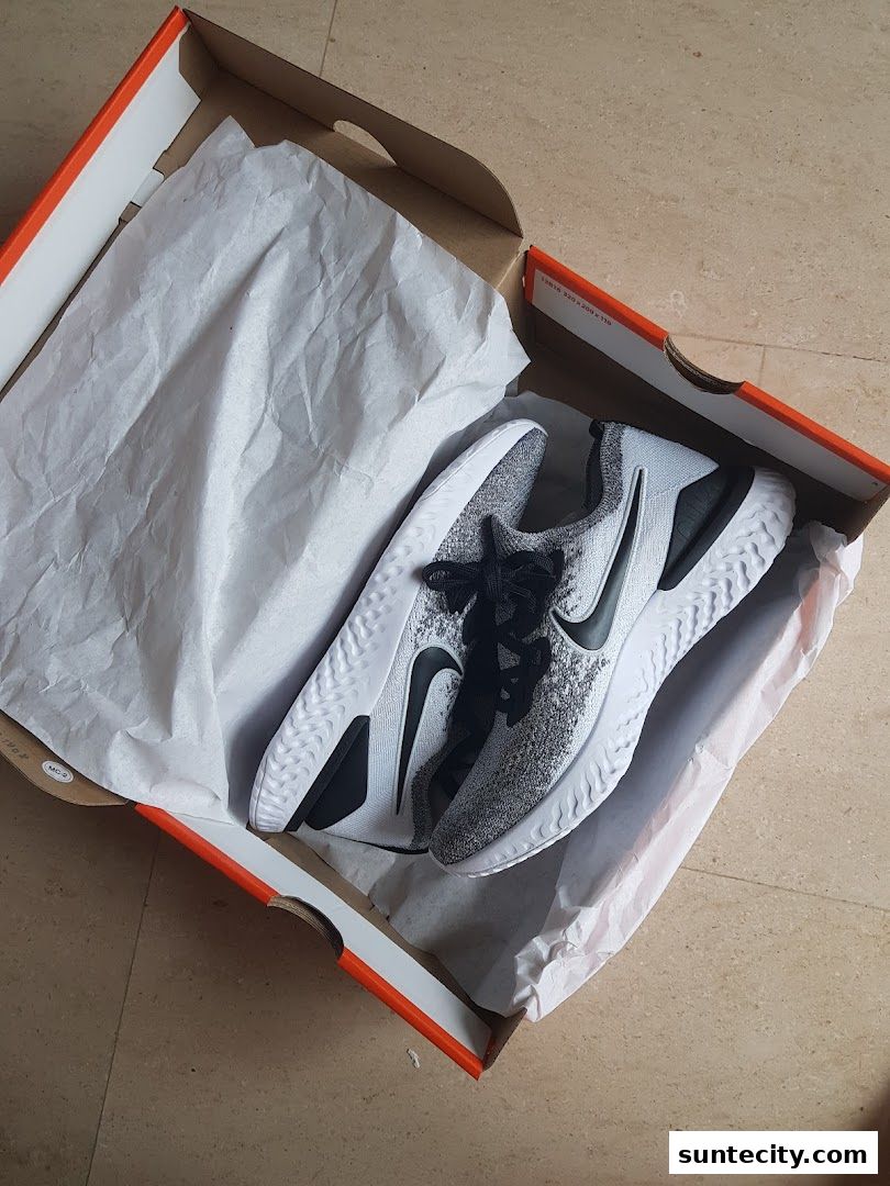A pair of white and black Nike running shoes in an open Nike shoebox.