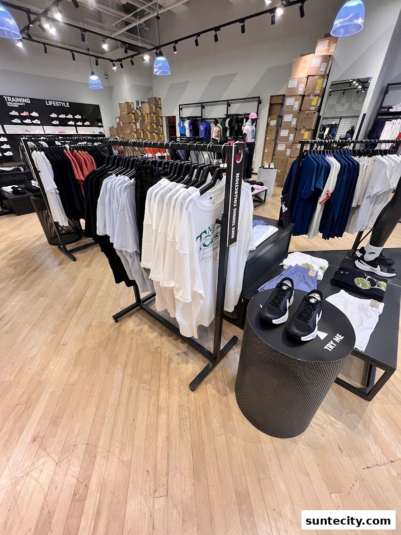 Interior view of a Nike store showcasing apparel and footwear, with racks of clothing and display tables.