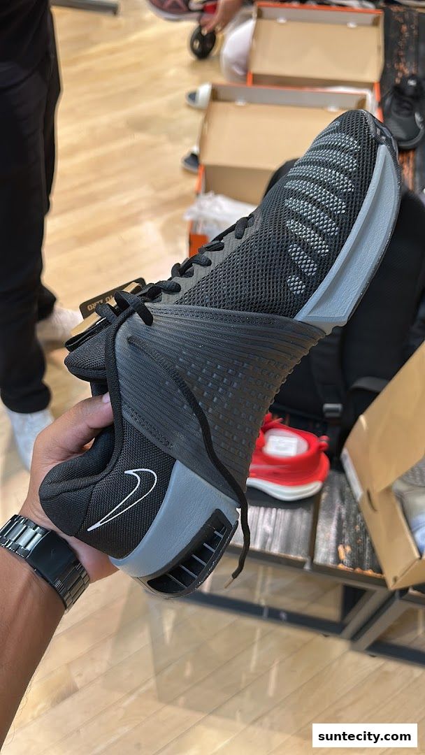 A person holds a black Nike athletic shoe with a grey sole and white swoosh logo.