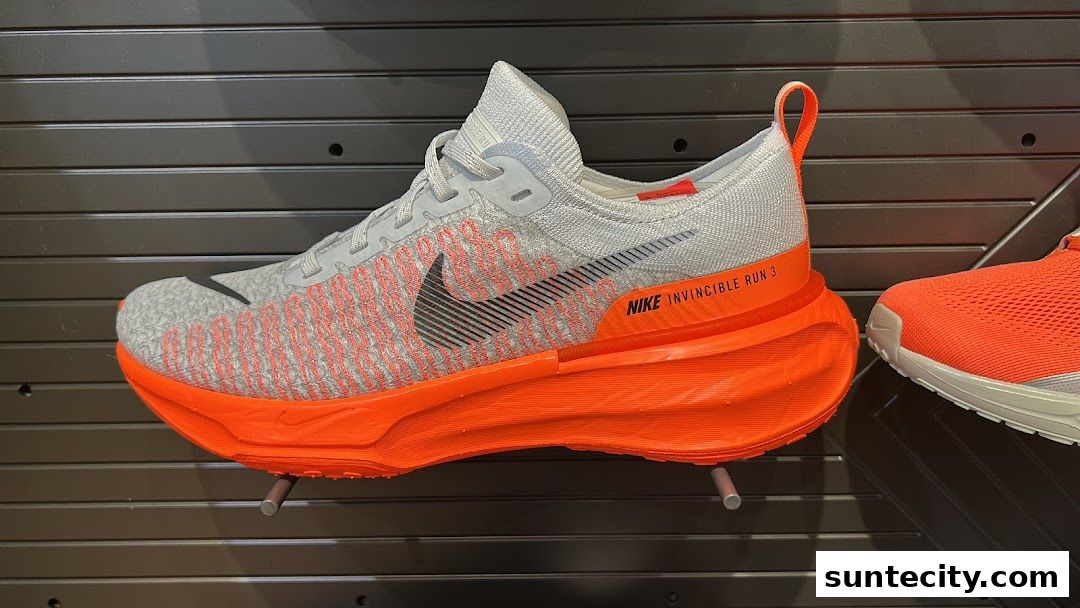 A close-up view of a Nike Invincible Run 3 shoe with a grey and orange design.