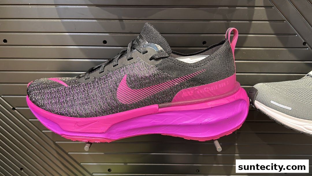 A close-up view of a black and pink Nike Invincible Run 3 running shoe on display.