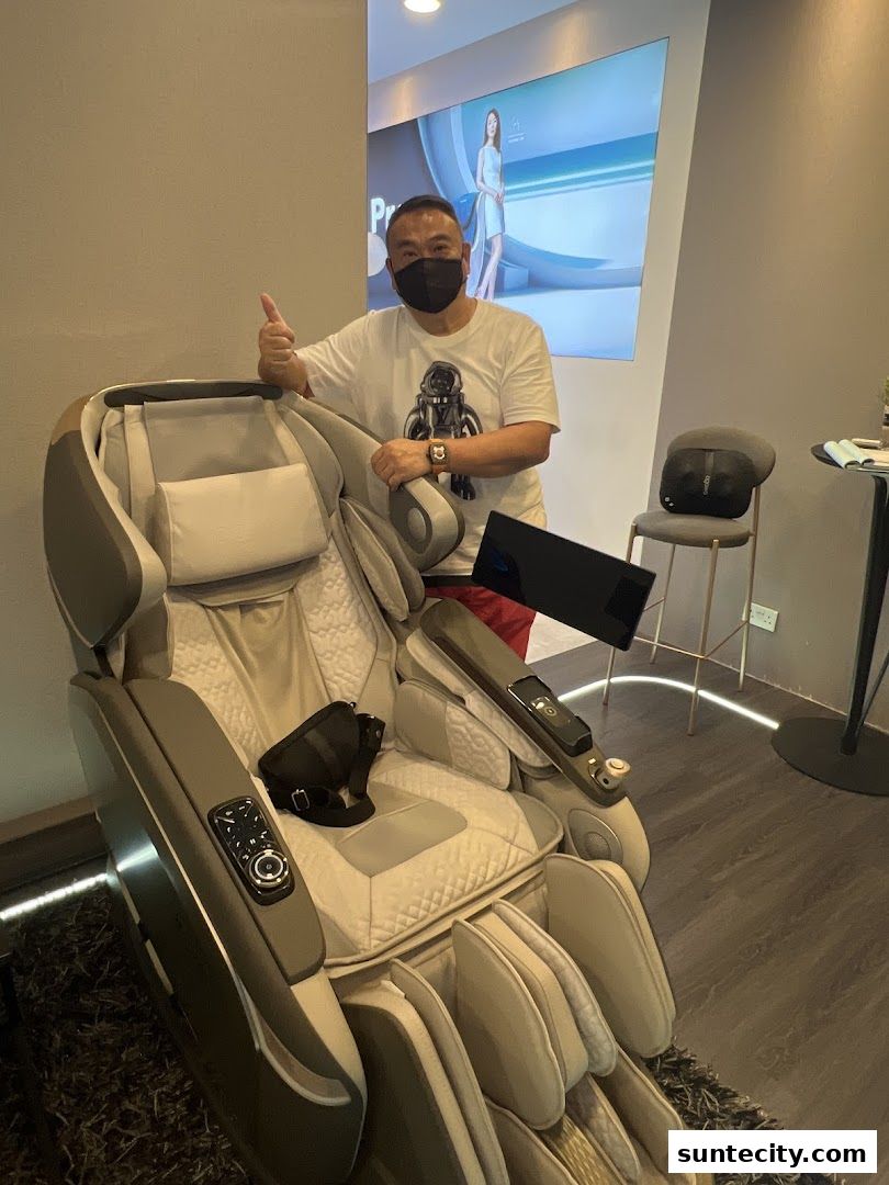 A man gives a thumbs up next to a luxurious massage chair in a retail store.