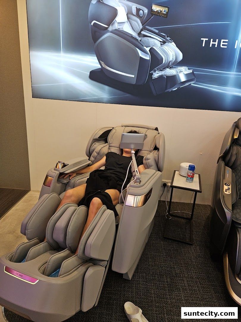 A person relaxing in an Ogawa massage chair with a tablet in front of them.