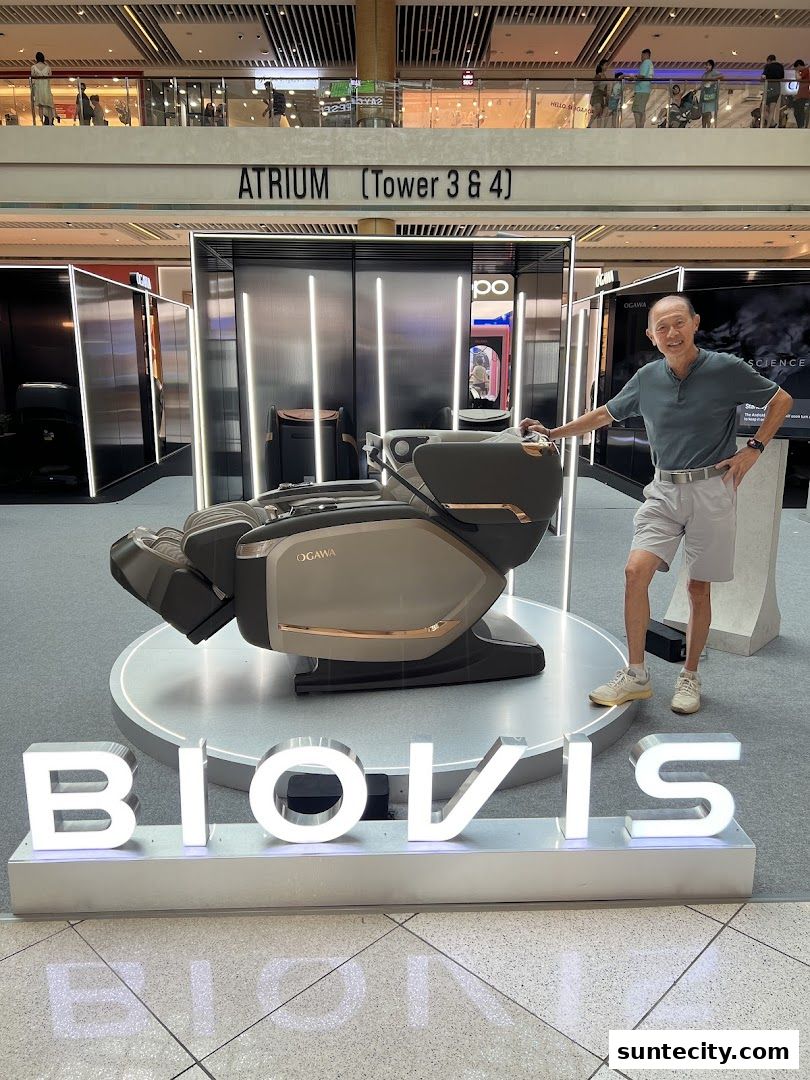 A man stands next to an Ogawa massage chair in a modern display at Suntec City.
