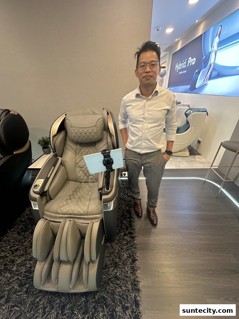 A man stands next to a luxurious massage chair in a modern retail store.