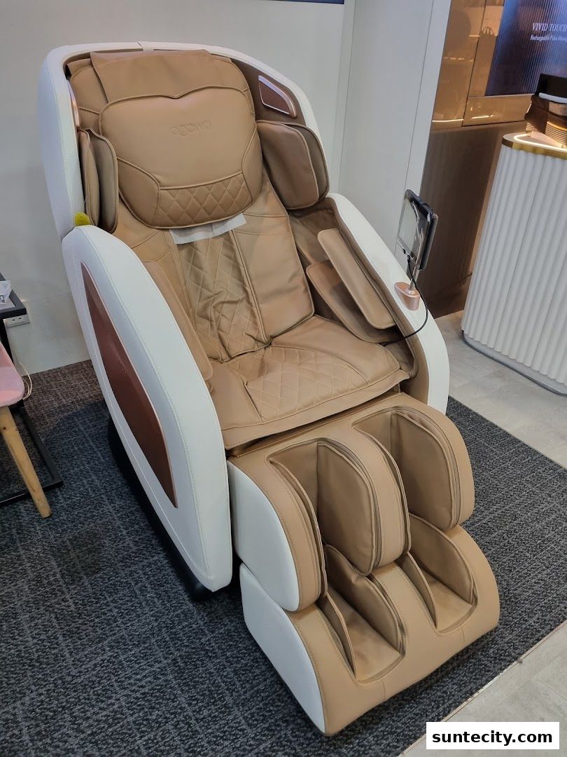 A luxurious beige and white massage chair with a footrest is displayed on a grey carpet.