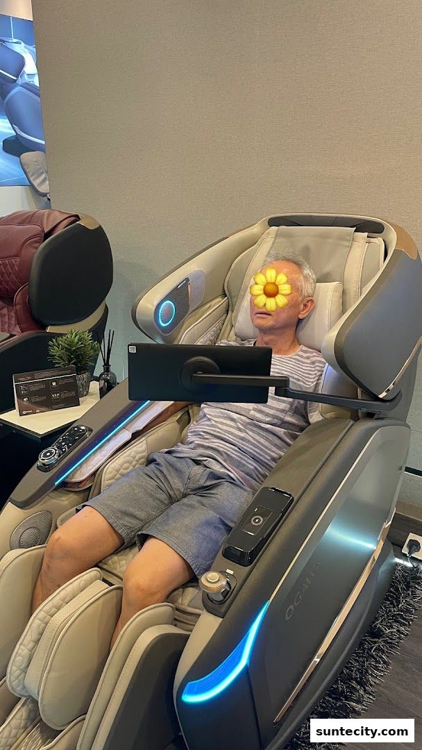 A man relaxes in a modern massage chair with a tablet attached.
